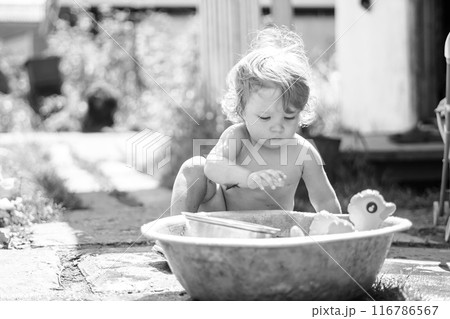 A little boy is bathing in a basin 116786567