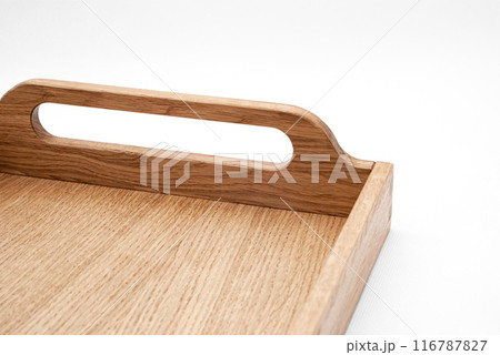 Elegant solid oak wood tray with dovetail joints and carved handles on the sides for easy carrying closeup view on white background 116787827