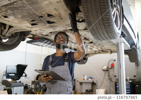 Mechanic inspecting car on lift in auto repair shop Mechanic inspecting car on lift in auto repair shop 116787865