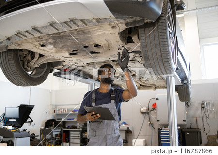 Mechanic inspecting car on lift in auto repair shop Mechanic inspecting car on lift in auto repair shop 116787866