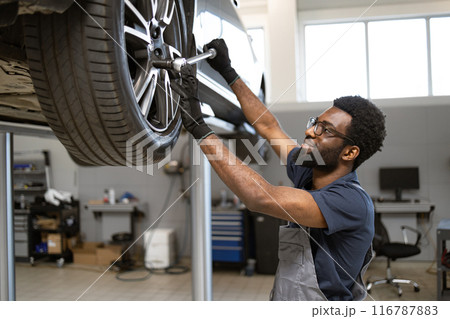 Mechanic working on car wheel in auto repair shop 116787883