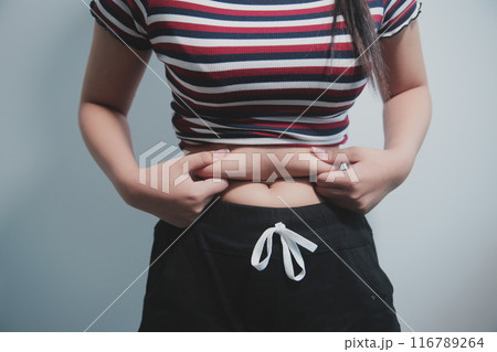 Women body fat belly. Obese woman hand holding excessive belly fat. diet lifestyle concept to reduce belly and shape up healthy stomach muscle. 116789264