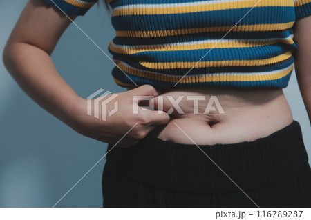 Women body fat belly. Obese woman hand holding excessive belly fat. diet lifestyle concept to reduce belly and shape up healthy stomach muscle. Women body fat belly. Obese woman hand holding excessive belly fat. diet lifestyle concept to reduce belly and shape up healthy stomach muscle. 116789287