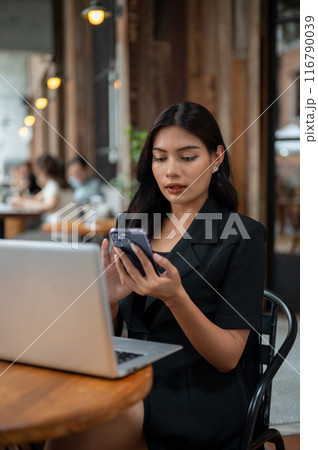 An attractive Asian businesswoman is using her smartphone while working remotely from a cafe. 116790039