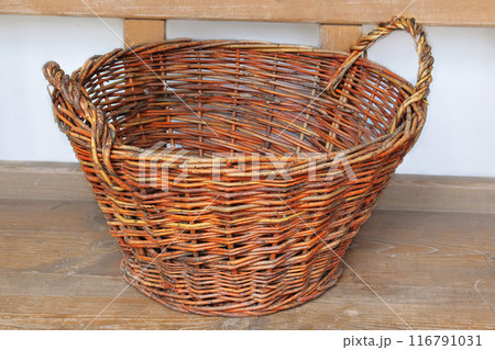Retro straw basket on a wooden bench. Vintage container in cottage kitchen. Country life. 116791031