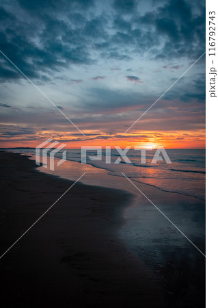 Experience a sunset on a peaceful beach, feeling the tranquil twilight atmosphere by the water Experience a sunset on a peaceful beach, feeling the tranquil twilight atmosphere by the water 116792743