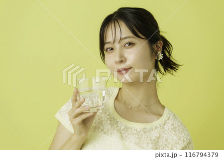 黄色背景のお水の入ったコップを持つ若い女性のポートレート 黄色背景のお水の入ったコップを持つ若い女性のポートレート 116794379