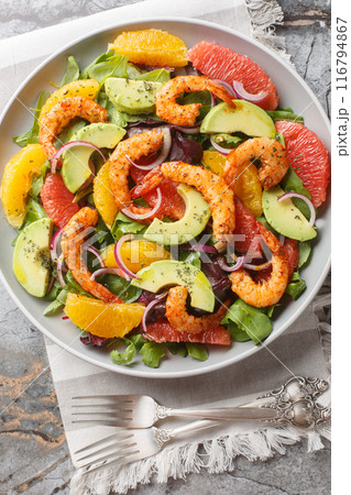 Citrus Cajun Shrimp Salad loaded with greens, shrimp, citrus fruits, and avocado closeup on the plate. Vertical top view 116794867
