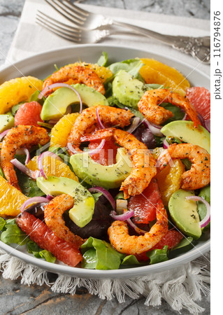Fresh Cajun shrimp salad with oranges, avocado, grapefruit and leafy greens close-up in a plate. Vertical 116794876