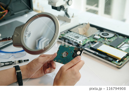 Repairman Looking At Disk Through Magnifier 116794908