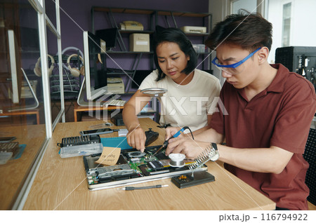Colleagues Repairing Laptop Together In Workshop Colleagues Repairing Laptop Together In Workshop 116794922