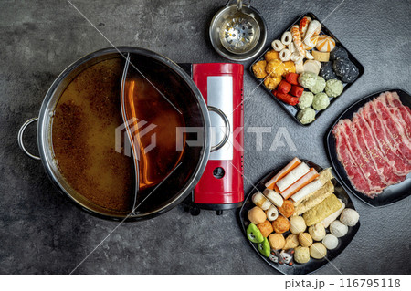 A red pot with a lid sits on a counter next to a red burner 116795118