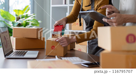 Small Business Owner Packing Boxes for Shipping in Modern Office with Laptop and Tablet Small Business Owner Packing Boxes for Shipping in Modern Office with Laptop and Tablet 116795707
