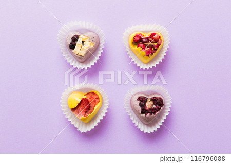 chocolate sweets in the form of a heart with fruits and nuts on a colored background. top view with space for text, holiday concept 116796088