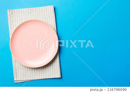 Top view on colored background empty round pink plate on tablecloth for food. Empty dish on napkin with space for your design 116796090