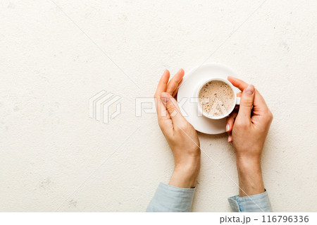 Minimalistic style woman hand holding a cup of coffee on Colored background. Flat lay, top view cappuccino cup. Empty place for text, copy space. Coffee addiction. Top view, flat lay 116796336