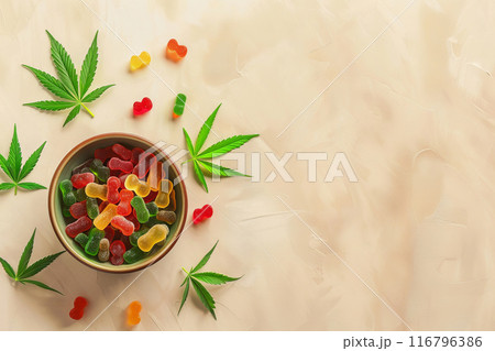 CBD Gummies with Cannabis Leaves in Bowl on Beige Background 116796386