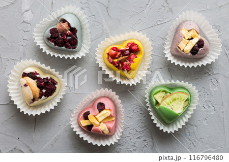 chocolate sweets in the form of a heart with fruits and nuts on a colored background. top view with space for text, holiday concept 116796480