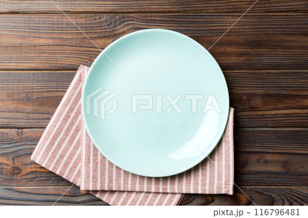 Top view on colored background empty round blue plate on tablecloth for food. Empty dish on napkin with space for your design 116796481