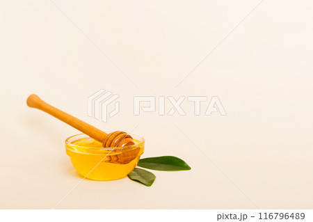 Honey in jar with leaves and honey dipper on colored background top view with copy text 116796489