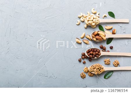 mixed nuts in white wooden spoon. Mix of various nuts on colored background. pistachios, cashews, walnuts, hazelnuts, peanuts and brazil nuts 116796554