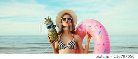 Summer vacation, tourism, happy young woman with swimming inflatable ring, pineapple on the beach 116797050