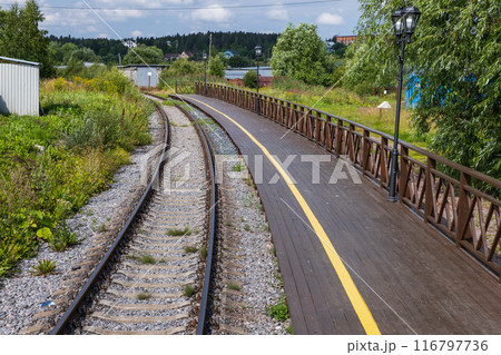 An empty railway track turning left along a station platform 116797736
