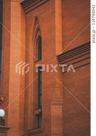 The high, narrow window of the church. The red brick wall of the church 116798042