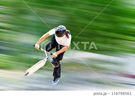 Young man practicing Scootering (Freestyle Scootering) in the new SkatePark in the central park of Igualada, Barcelona, blurred background Young man practicing Scootering (Freestyle Scootering) in the new SkatePark in the central park of Igualada, Barcelona, blurred background 116798561