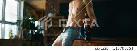 Banner. Young man with athletic body leaned on wooden bar counter and holding glass bottle with soda and straw. Refreshing. 116799251
