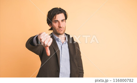 Upset businessman showing thumb down in brown studio 116800782
