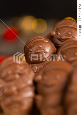 Chocolates in the shape of Christmas figures on the background of a flashing garland 116802178