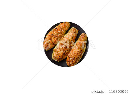 Zucchini halves baked with cheese, tomatoes, meat or meat substitute 116803093