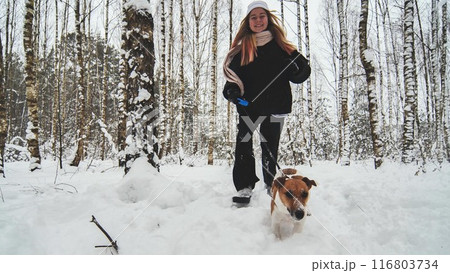 A girl and her Jack Russell Terrier dog are running through the woods. 116803734