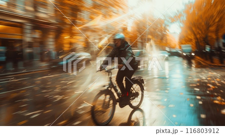 Man riding a bicycle on a rainy city street in motion blur during autumn 116803912