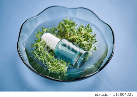 The bottle of serum is blue in water with seaweed. The bottle of serum is blue in water with seaweed. 116804323