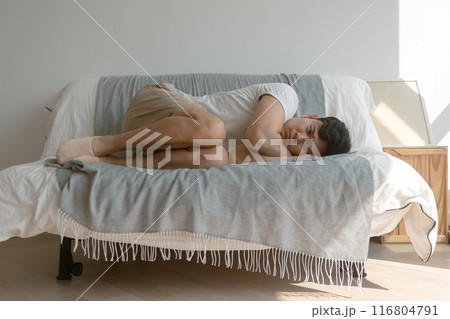 Man curled up on the sofa in the apartment. Man curled up on the sofa in the apartment. 116804791