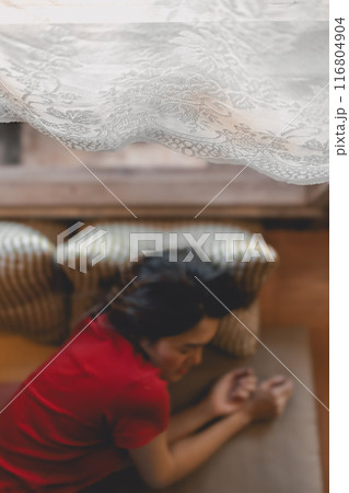 Woman in red taking a nap, resting in the living room. 116804904