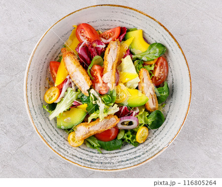 Salad with chicken, avocado, mango, cherry tomatoes, lettuce, onion removal, kumquat, on a gray background. 116805264