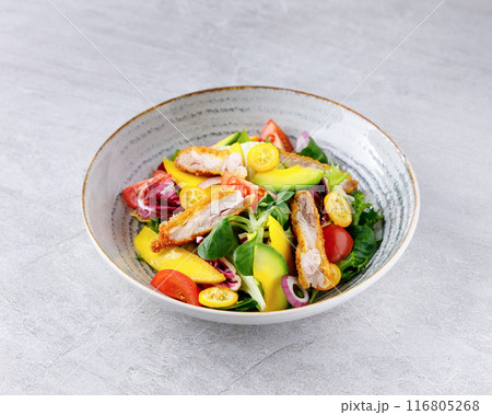 Salad with chicken, avocado, mango, cherry tomatoes, lettuce, onion removal, kumquat, on a gray background. 116805268