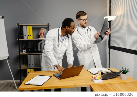 Two men in white lab coats analyzing xray 116806326