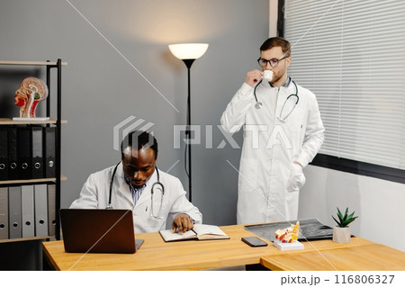 Doctor discussing diagnosis with young colleague in office 116806327