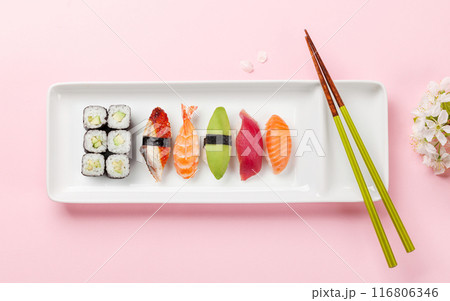 Sushi plate adorned with cherry blossom branch and chopsticks, epitomizing Japanese food culture 116806346