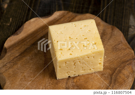 a piece of cheese with holes on the table 116807504