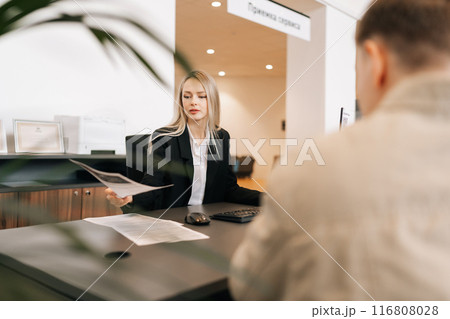 Serious female financial advisor, attorney lawyer or bank manager consulting unrecognizable male client investor receiving document at business meeting, reviewing legal paper file, planning taxes. Serious female financial advisor, attorney lawyer or bank manager consulting unrecognizable male client investor receiving document at business meeting, reviewing legal paper file, planning taxes. 116808028