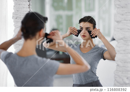 Facial skin care. A woman is doing a face massage using gouache stones. 116808392
