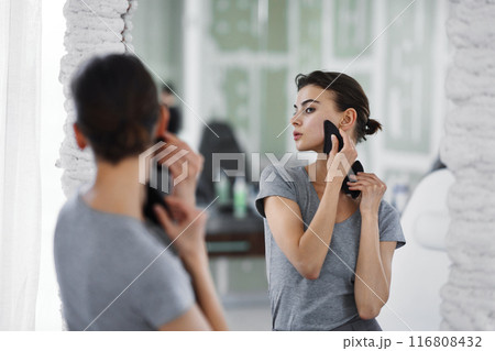 Facial skin care. A woman is doing a face massage using gouache stones. 116808432