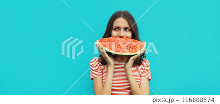 Summer portrait of happy young woman eating fresh slice of watermelon on blue background 116808574