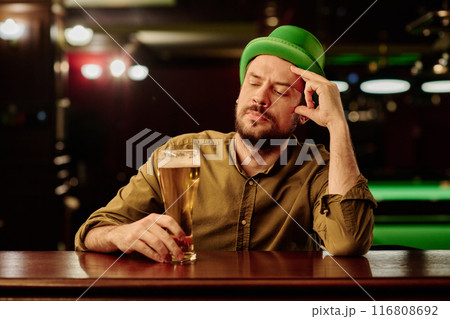 Man looking at glass of beer by counter 116808692