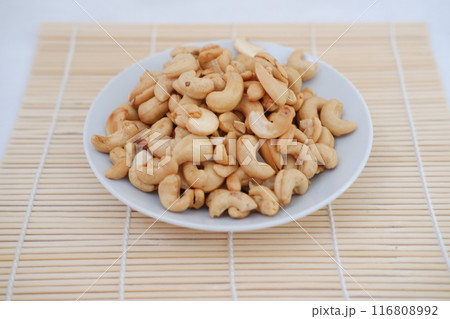 Roasted cashew nuts in white bowl on bamboo mat, stock photo 116808992